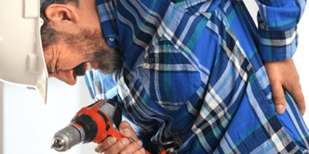 A workman in a hard hat is in pain from work related back injuries.