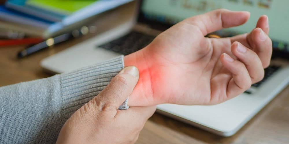 A close up of someone holding their wrist because of pain.
