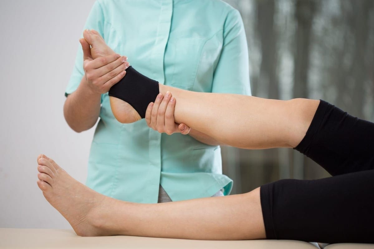 A chiropractor treats a persons ankle.