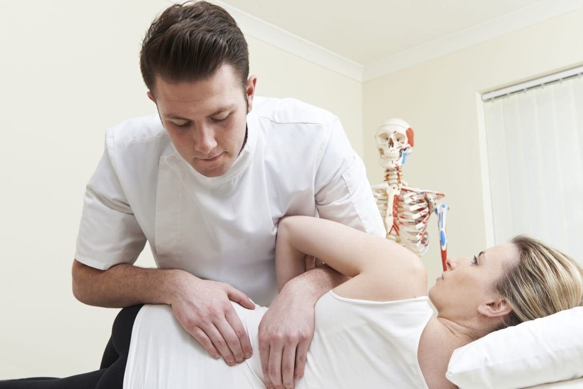 A woman is getting a spinal adjustment from a chiropractor after an auto accident injury.