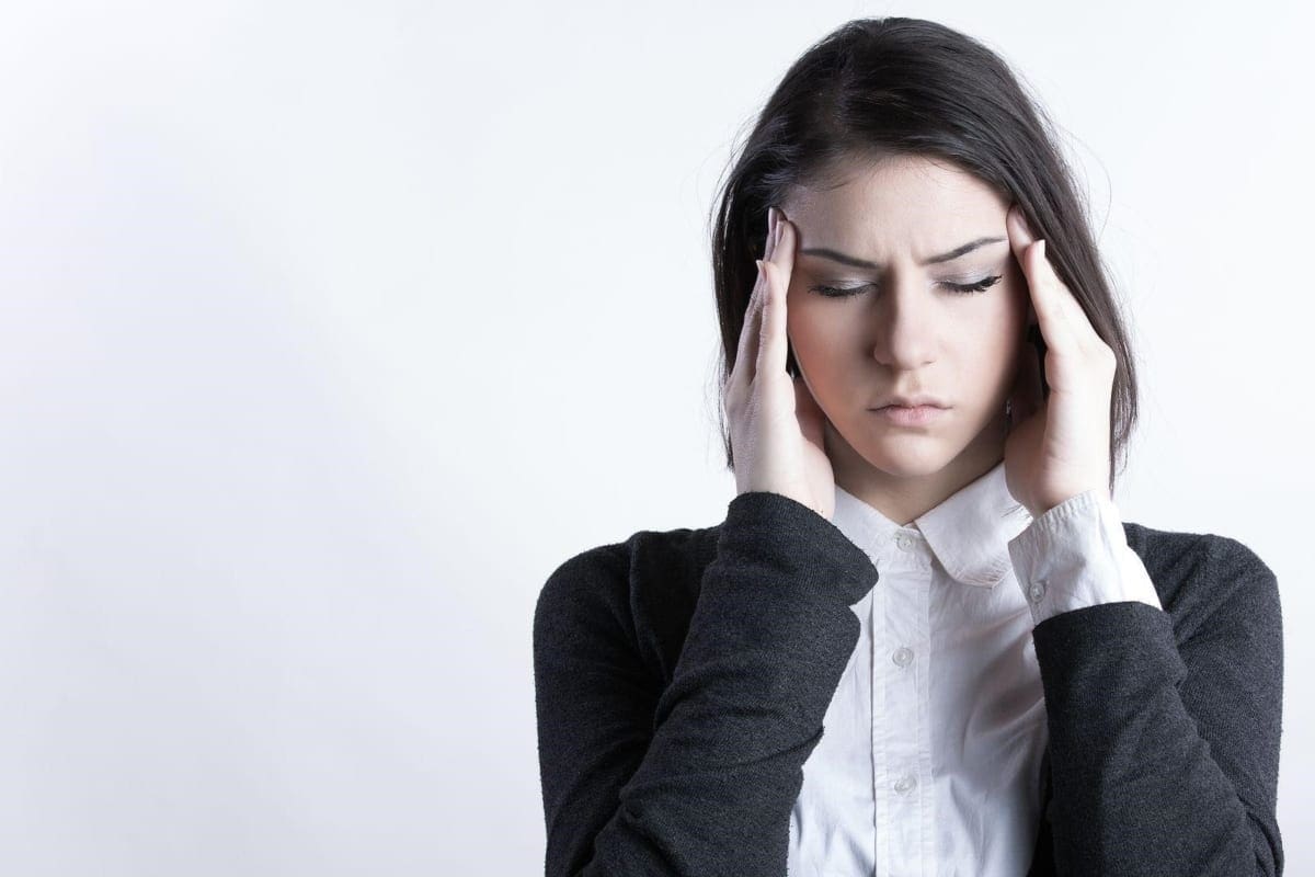 A woman rubs her temples because of a headache.