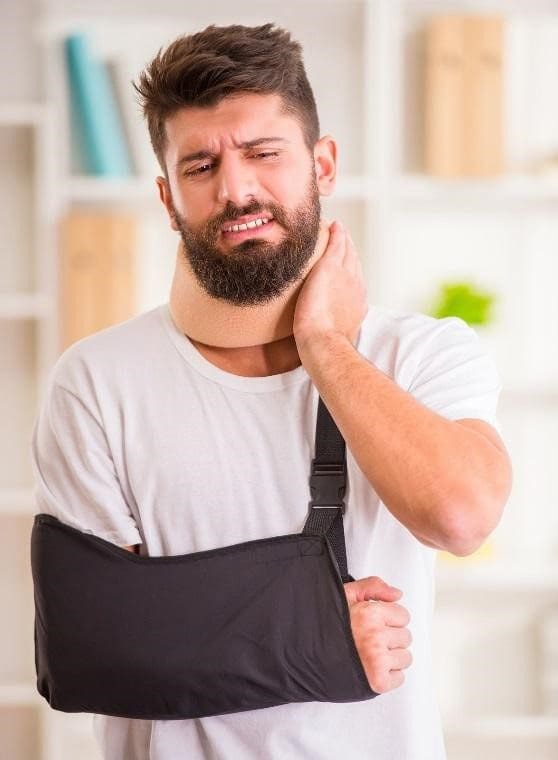 A man in a neck brace and arm sling suffers from injuries.