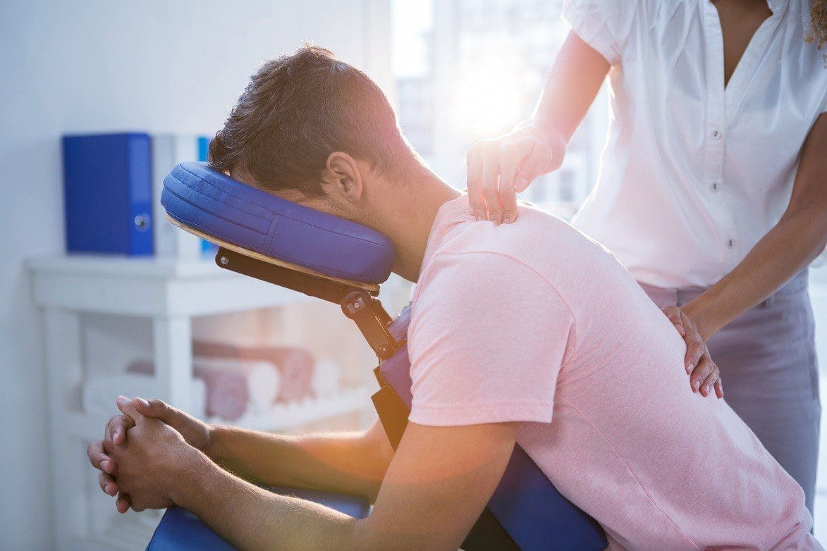 A chiropractor administers upper back treatment.