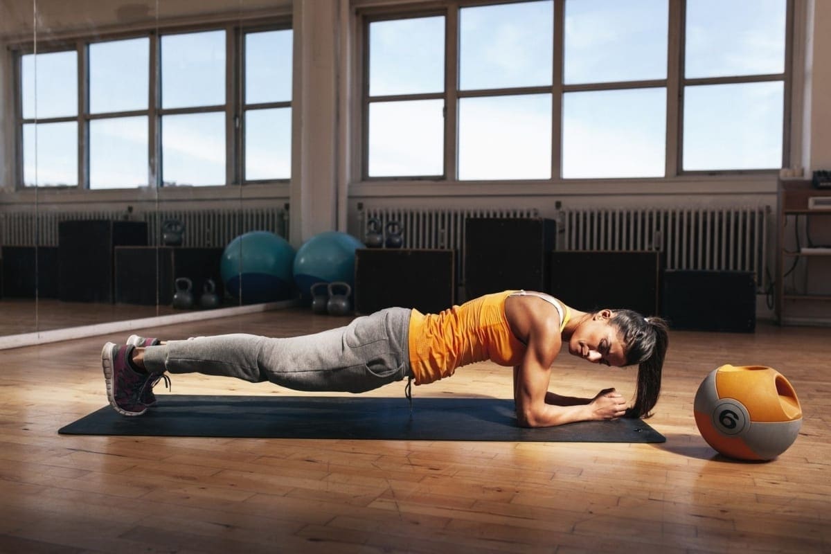 A woman is at a gym exercising her core on a gym matt.