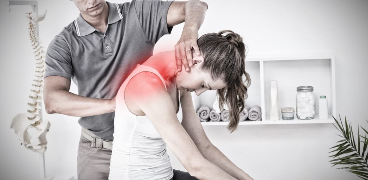 A Chiropractor examines a womans upper spine where she is experiencing pain.