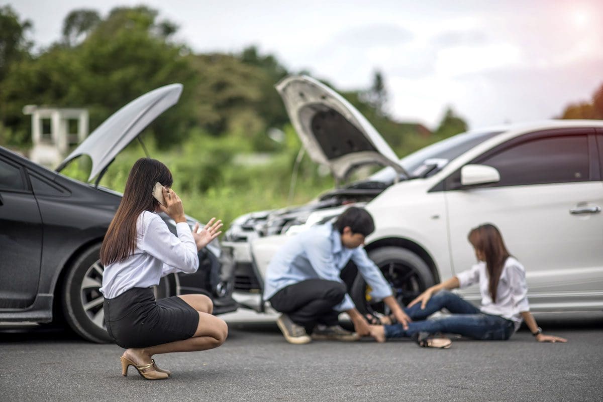 People are hurt after a car accident while a woman calls for help.