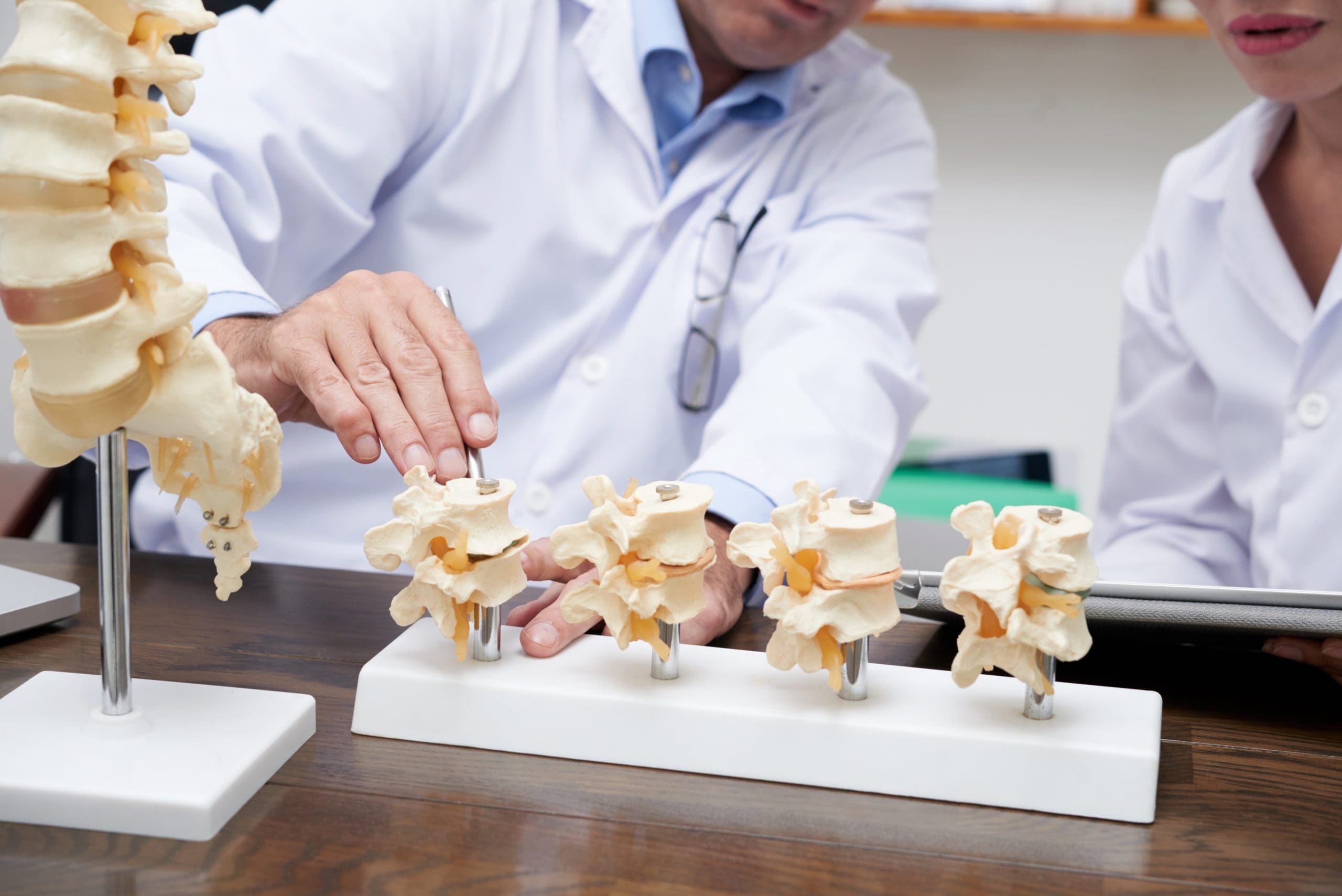 Doctor showing various spinal sections showing intervertebral disc space disease.