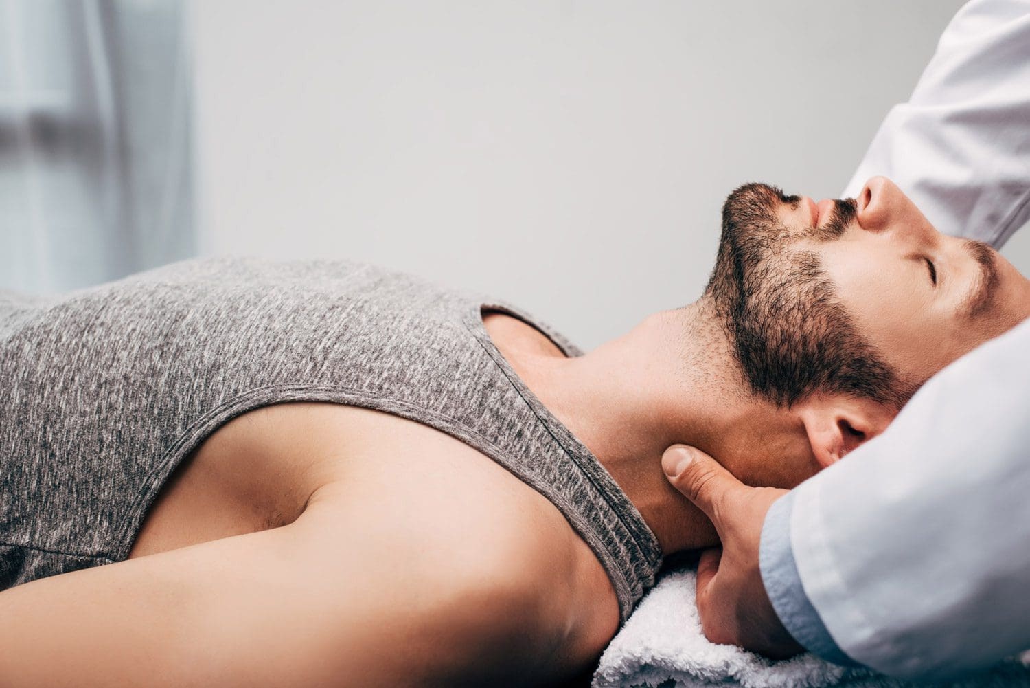A man is laying on his back while being treated for headaches at the Woodburn Chiropractic Clinic