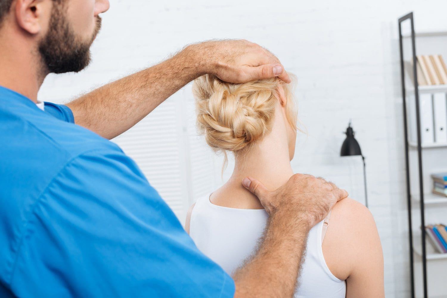 A woman is being treated for whiplash by a chiropractor.