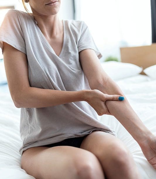 A woman is holding her arm because it hurts.
