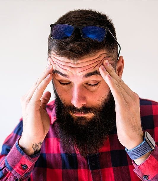 A man is rubbing his temples because he has a headache.