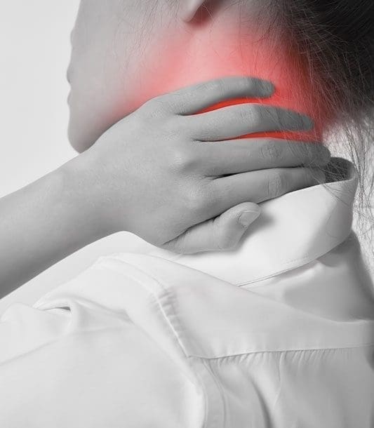 A woman is holding the back of her neck in pain.