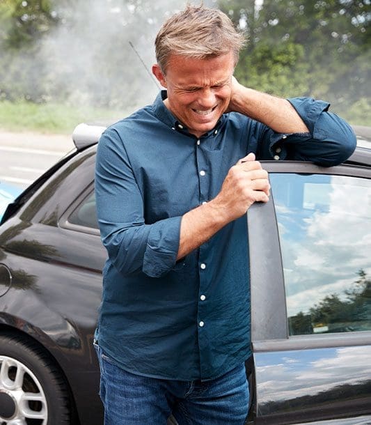 A man who was just in a car accident is in pain and holding the back of his neck in pain.