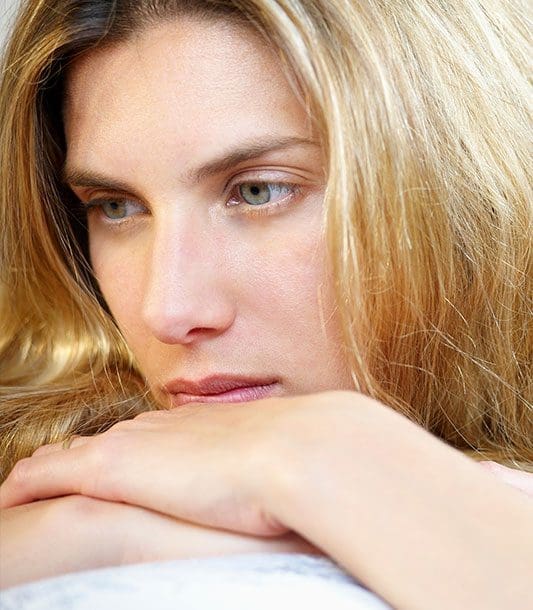 A woman looks very sad because she struggles with anxiety.