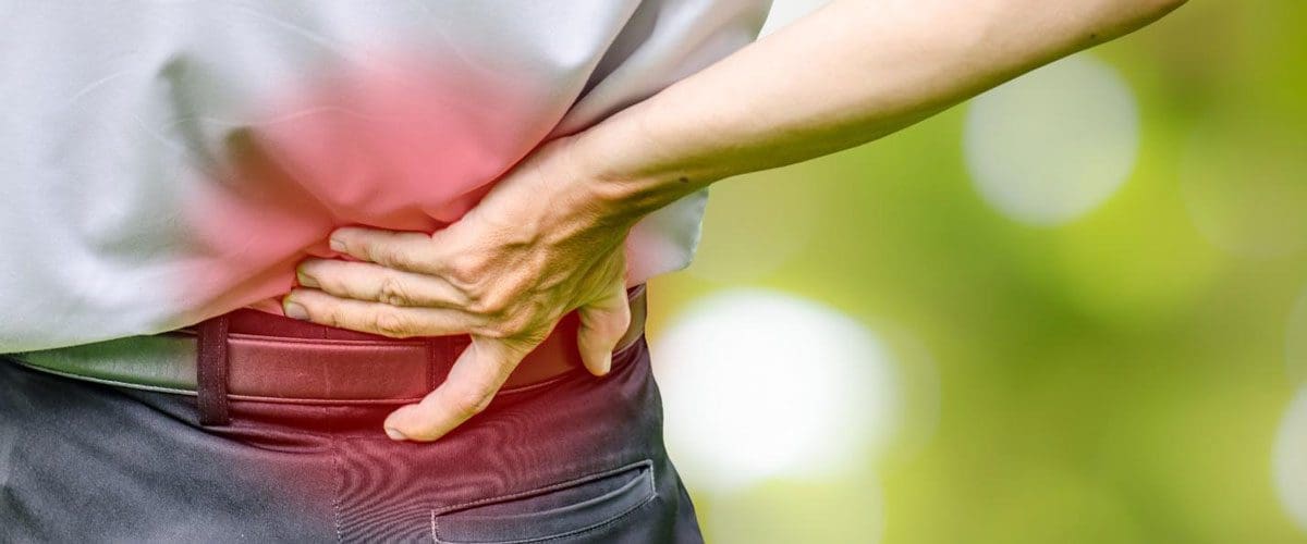 A man touching his aching lower back.