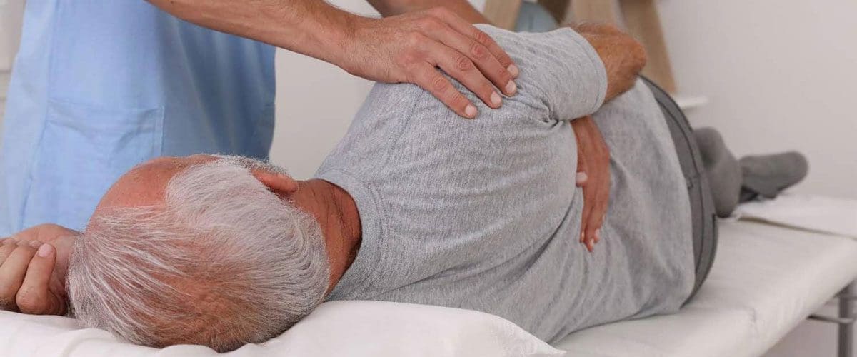 A man is laying on a chiropractic table getting an adjustment for back pain.