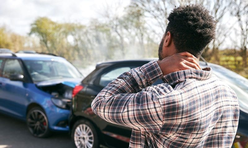 A man who was just in an auto accident is holding the back of his neck.