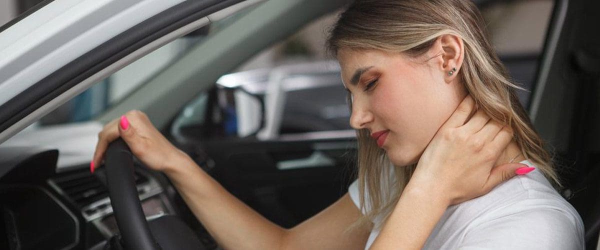 A woman grasps the back of her neck because of whiplash pain