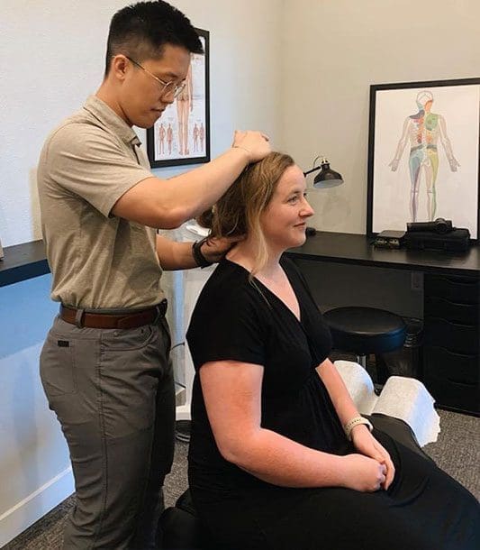 A chiropractor is administering a neck adjustment on a female patient.