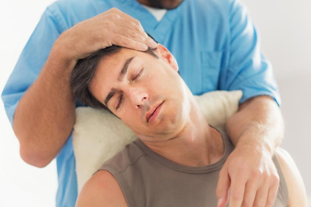 A man is getting a chiropractic neck adjustment to treat whiplash injuries.