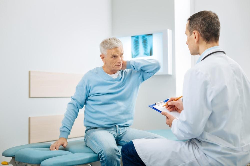 A chiropractor is examining a man to treat neck pain.
