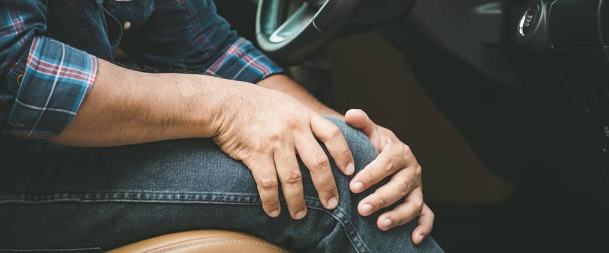 A man clutches his knee in pain.