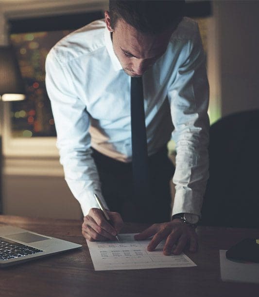 A lawyer is filling out paperwork at his desk.