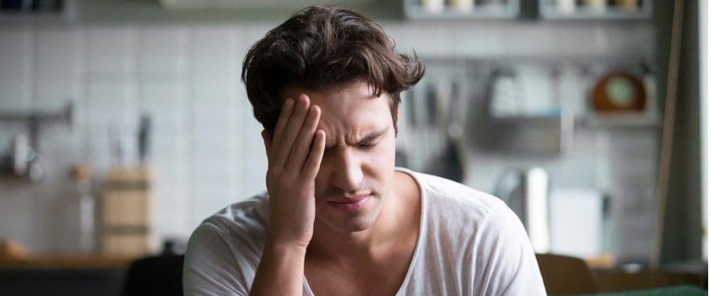 A man rubs his forehead because he is suffering from a migraine headache.