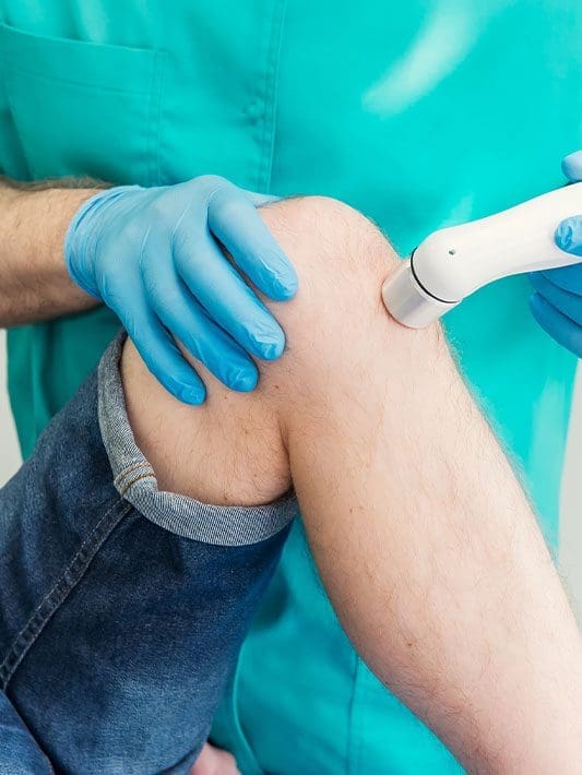 A chiropractor administering nerve root impingement knee treatment.
