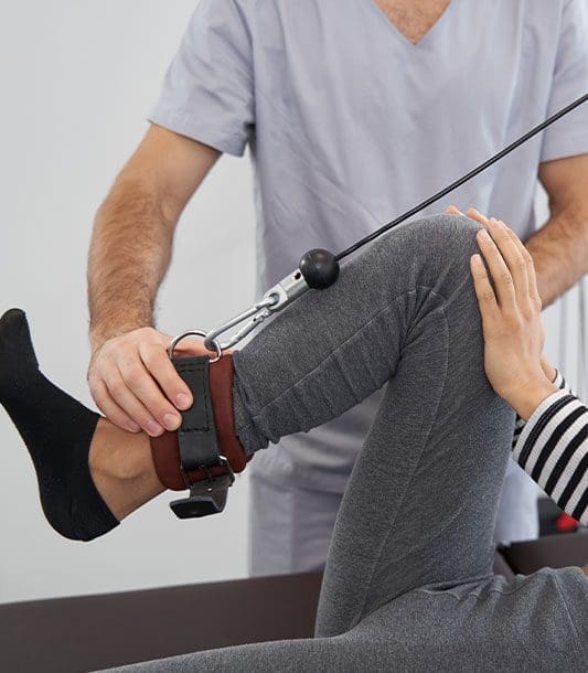 A woman is doing rehabilitation exercises with a chiropractor.