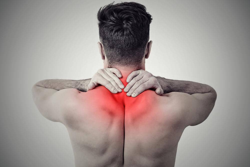 A man rubs his lower neck because of neck pain.