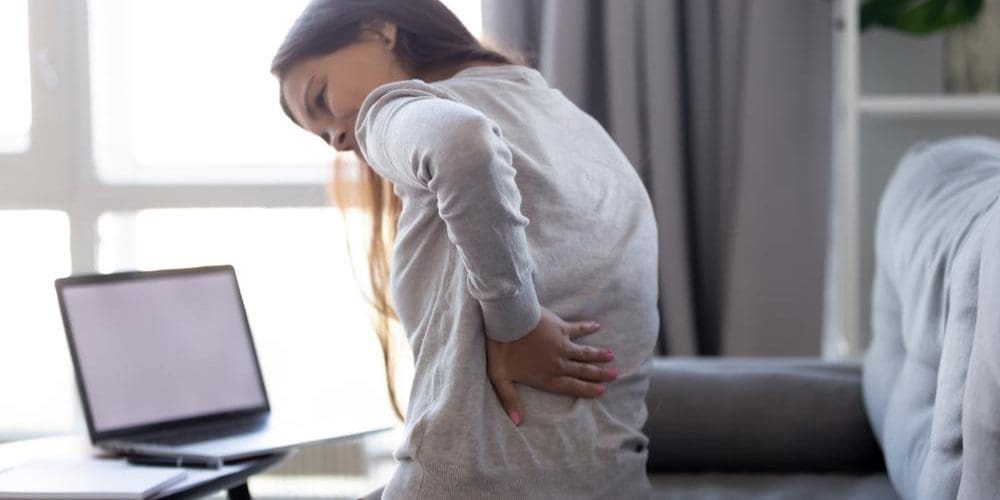 A woman is struggling to stand up because her back is stiff.