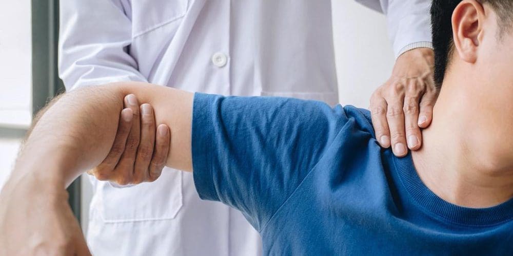 A chiropractor is treating a man for a shoulder injury.