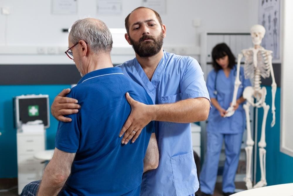  A chiropractor is examining and assessing a man's spinal cord injury.