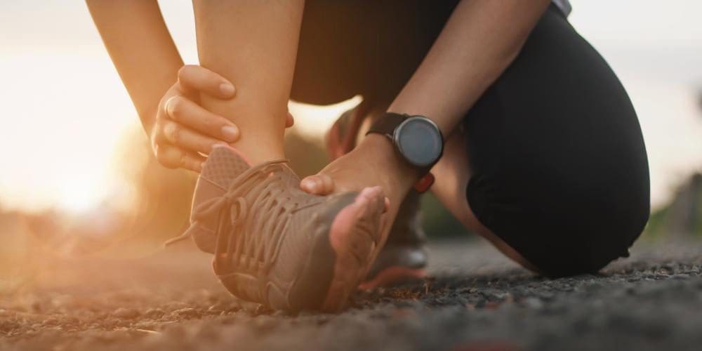 A runner holds her ankle after she sprained it.
