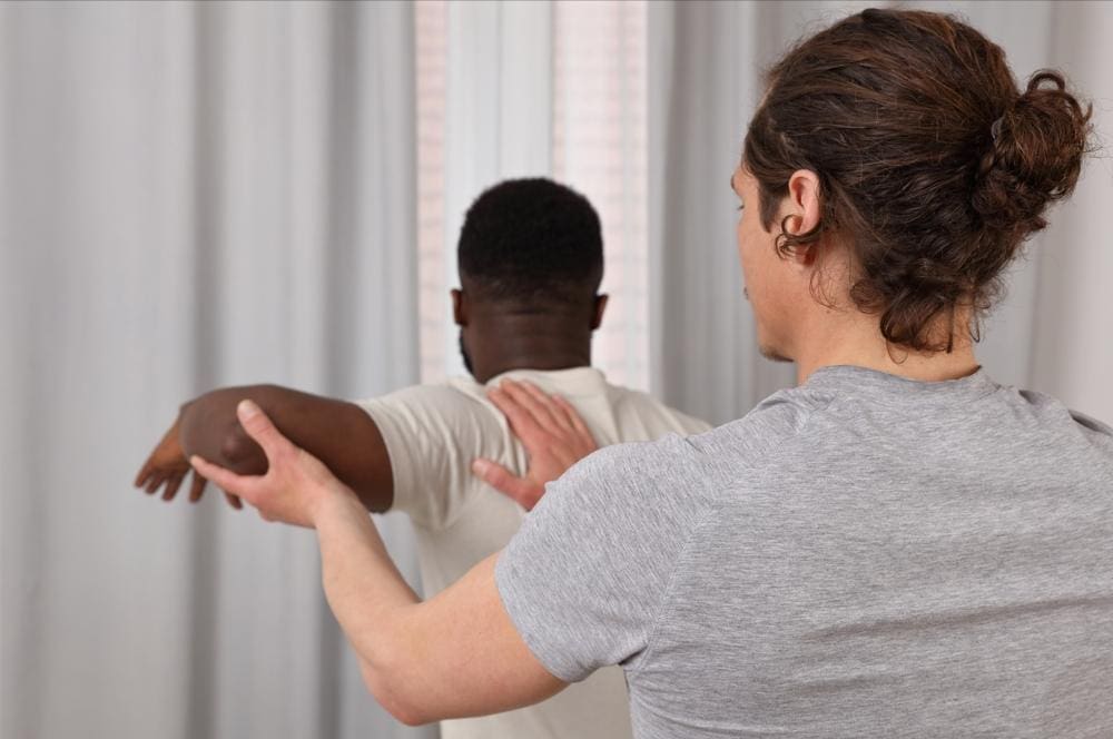 A chiropractor is treating a man for bursitis in his shoulder. 