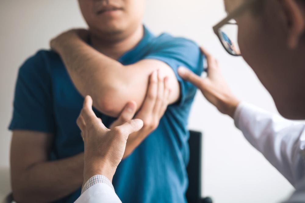 A chiropractor is examining a man's elbow to determine the best treatment for joint pain.