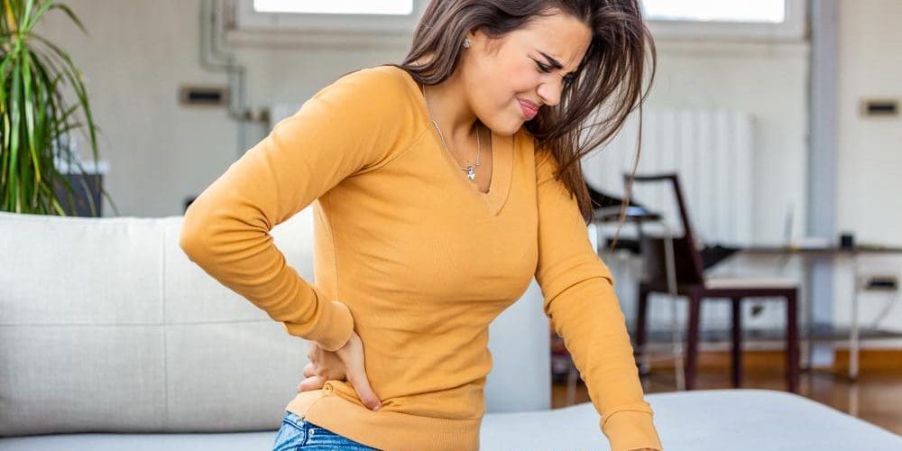 A woman is wincing in pain from nerve damage in her spine.