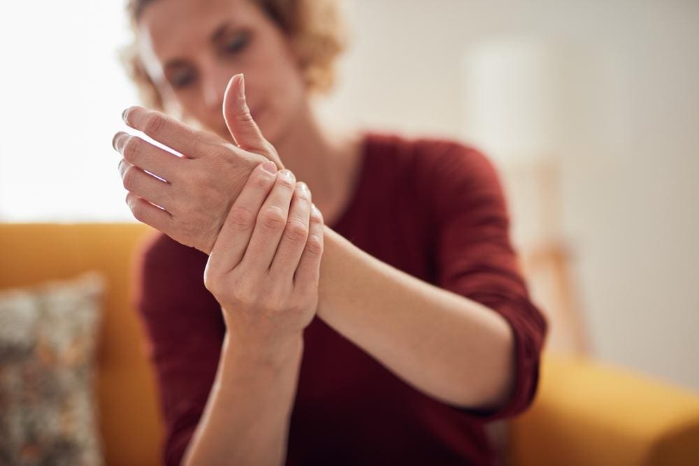 A woman is massaging her hand and wrist because of pain caused by nerve damage. 