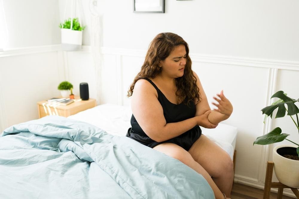 A woman is experiencing the pins and needles sensation and numbness in  her arm.