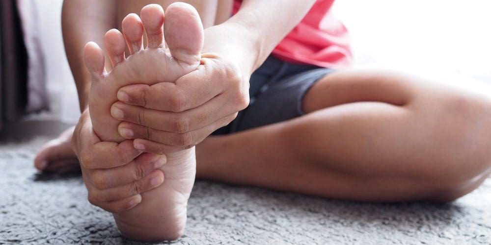 A man is rubbing the bottom of this foot because of plantar fasciitis pain.