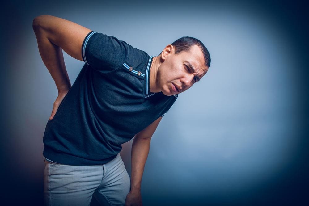 A man is in pain and cannot stand up straight because of sciatica. 
