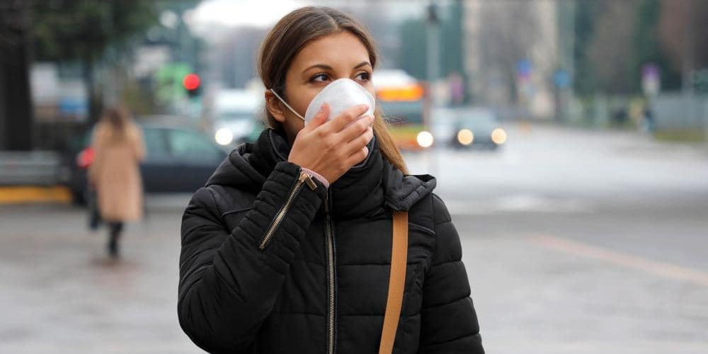 A woman is walking down the street in a Covid face mask.