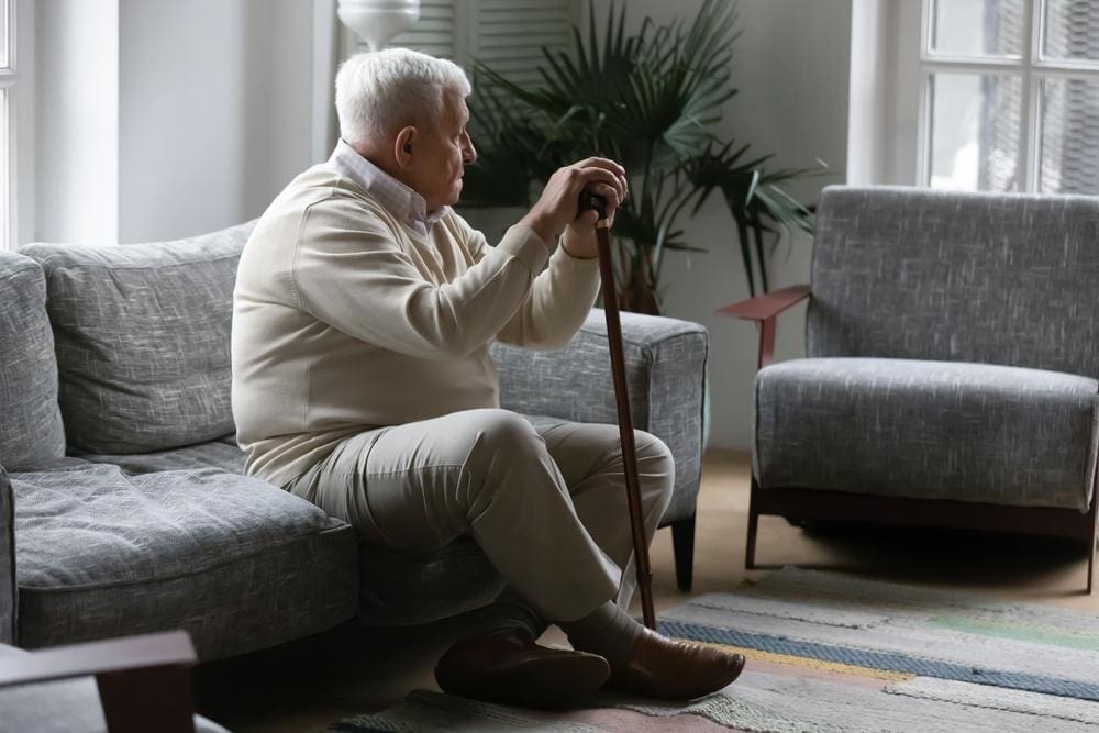 An elderly man is sitting in a waiting room waiting for a post surgical follow up.