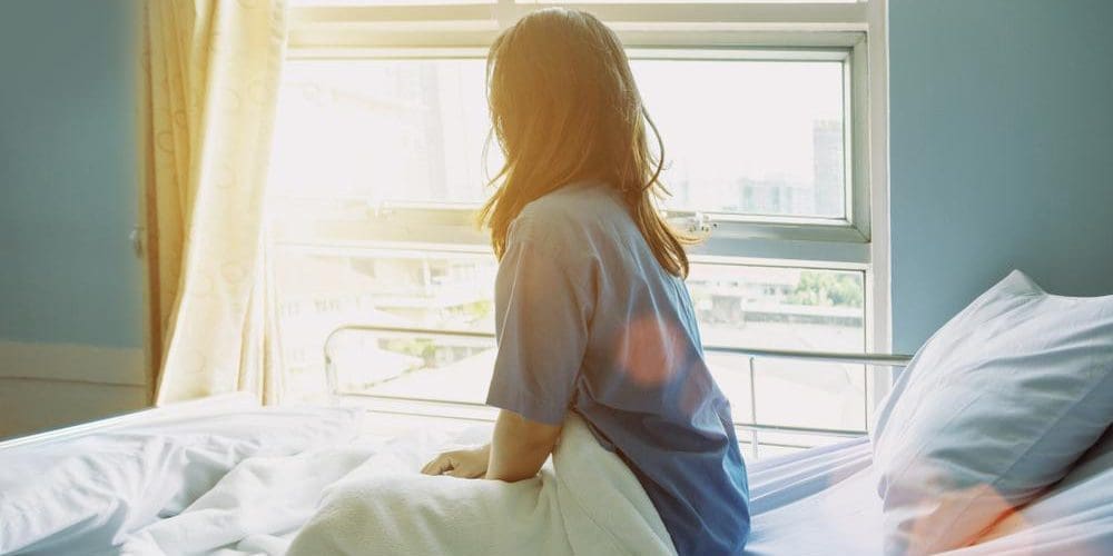 A woman is sitting in a hospital bed after surgery.