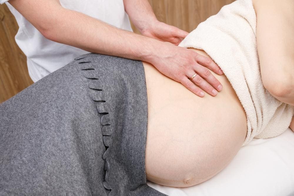 A chiropractor is treating a pregnant woman for back pain caused by her pregnancy.