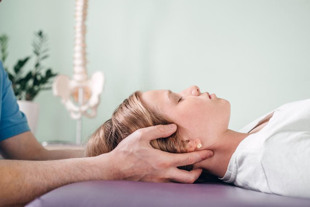 A young girl getting a gentle neck adjustment from a chiropractor. 
