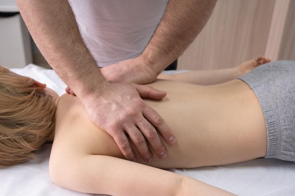 A boy is getting a chiropractic adjustment.  
