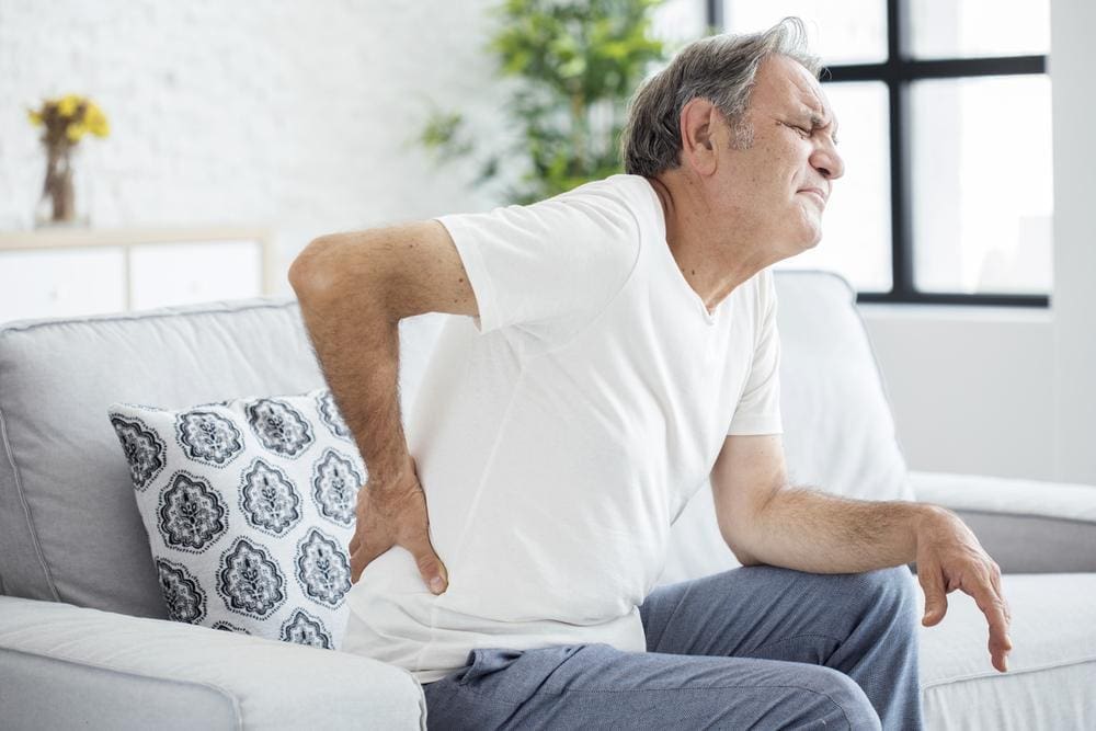 A man is in pain and cannot stand up because his back hurts too much.