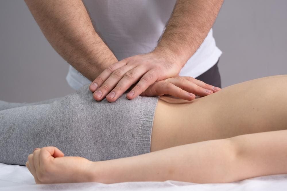 A chiropractor is administering a spinal adjustment on a woman to realign her spine after childbirth. 
